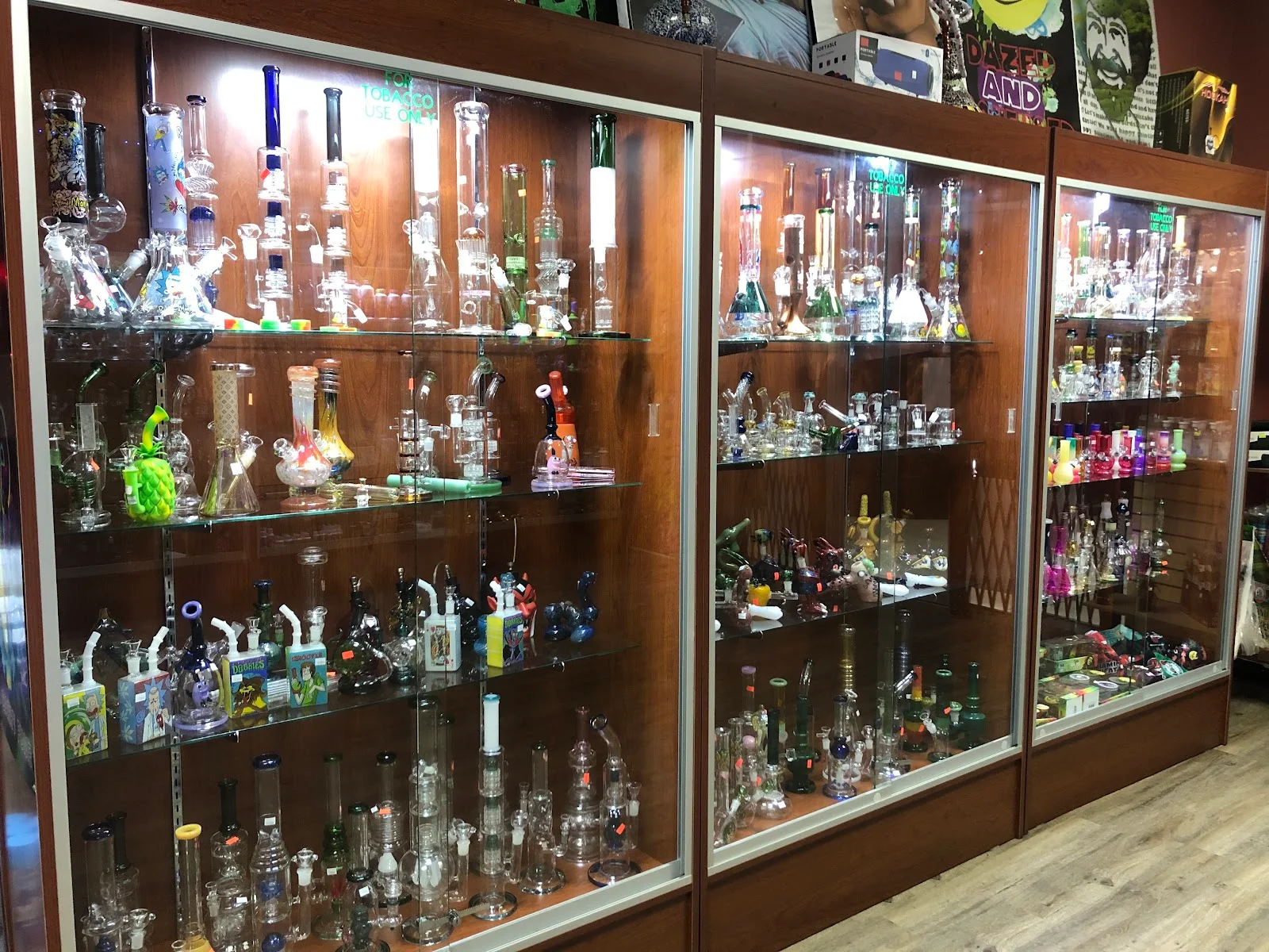 Three lit wooden display cabinets filled with glass water pipes and rigs