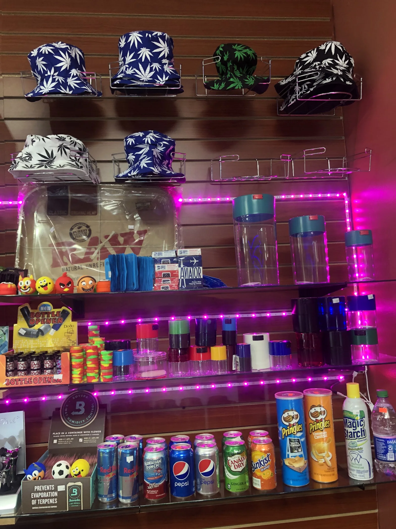 Pink neon lit shelving with leaf-print bucket hats, rolling trays and airtight jars