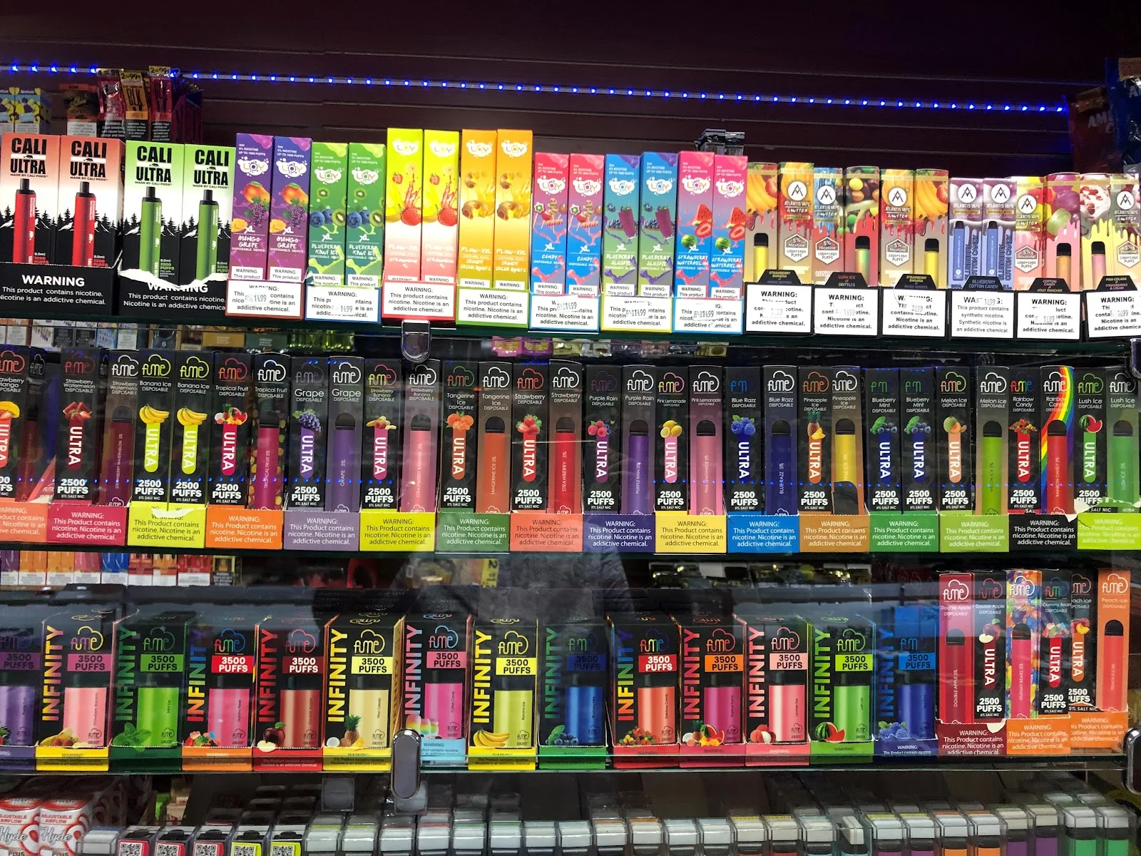 Rows of disposable vapes in coloured boxes along the shelf wall